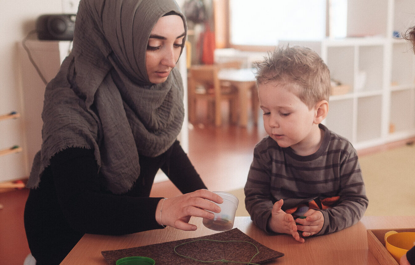 Erzieherin begleitet zwei Kinder bei einer Tischaktivität in der Krippe des Montessori Zentrum Ortenau