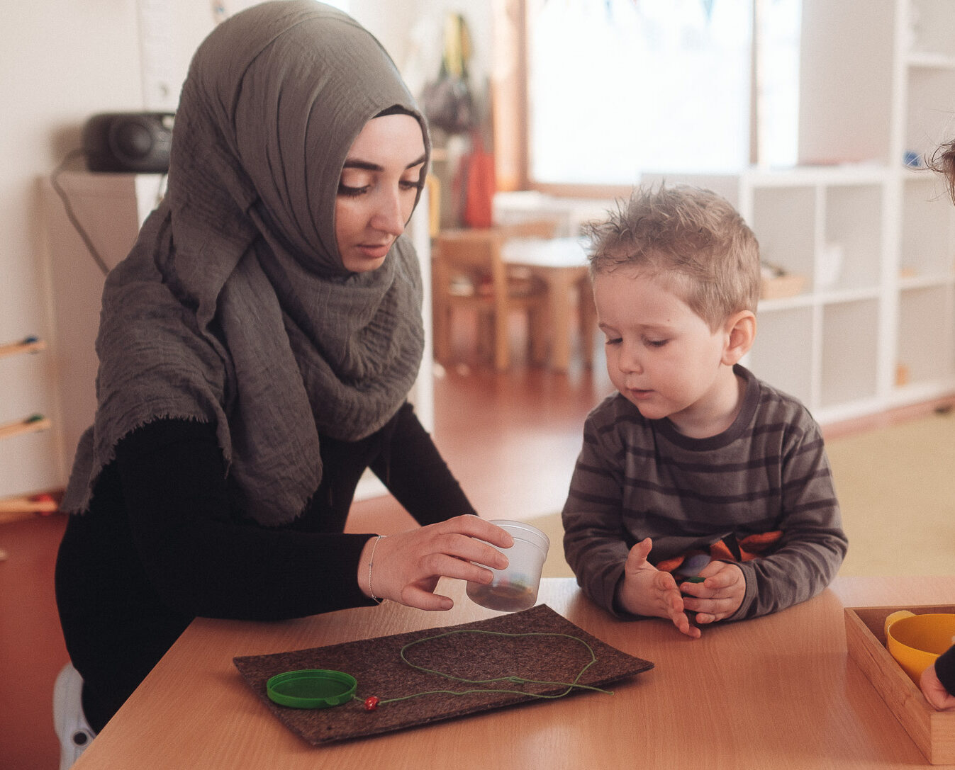 Erzieherin begleitet zwei Kinder bei einer Tischaktivität in der Krippe des Montessori Zentrum Ortenau
